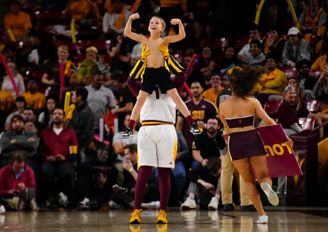 Sparky lifts a young ASU fan showing their muscles during a game at Desert Financial Arena.