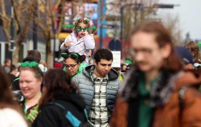 Charlotte Ritchey, 3, adjusts her shamrock glasses while getting a bird's-eye-view of the parade from atop her mother Sarah's shoulders as the family walks in the 29th. Annual St. Patrick's Day Parade in downtown Bremerton on Saturday, March 11, 2023.